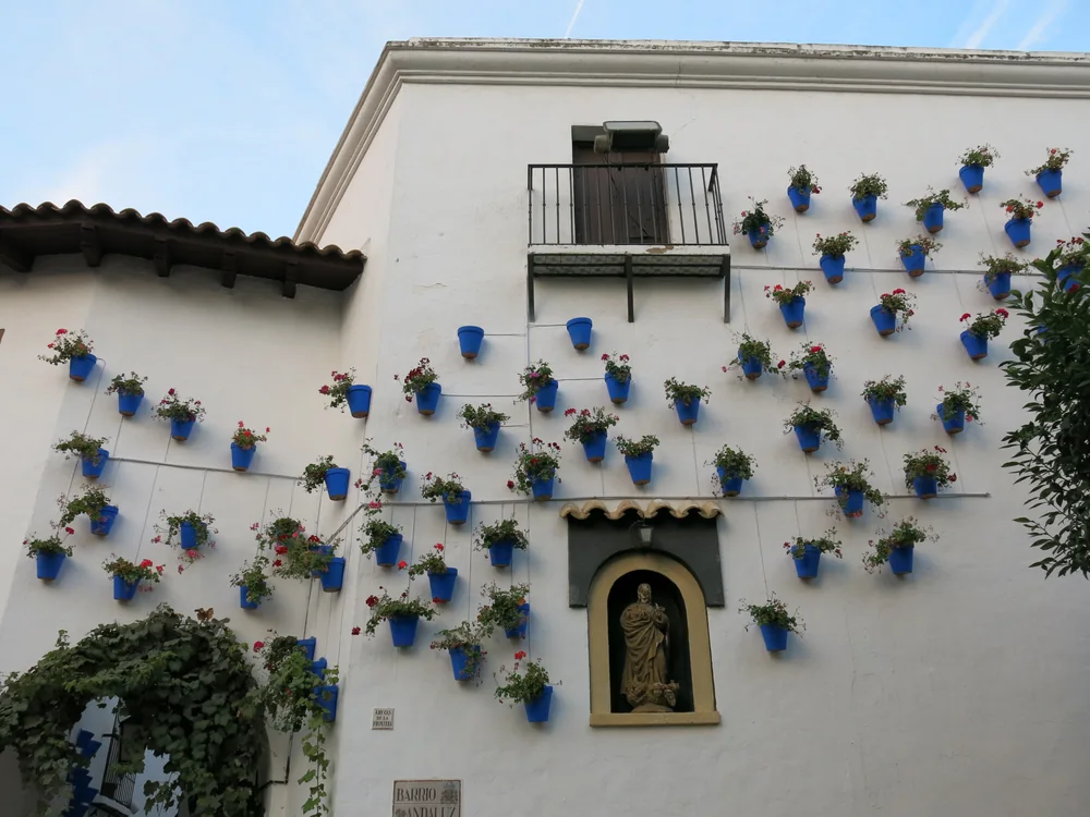 A whitewashed wall in Poble Espanyol's Andalusian quarter hung with blue flowerpots of red geraniums