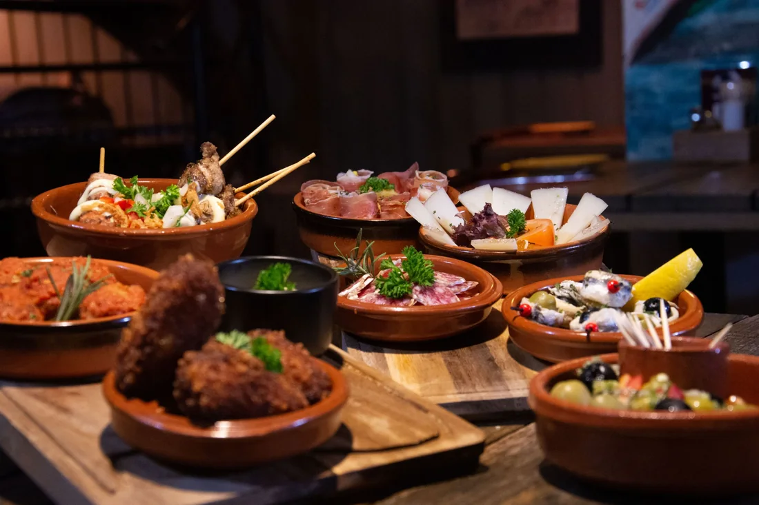 A spread of small Spanish tapas plates on a wooden table